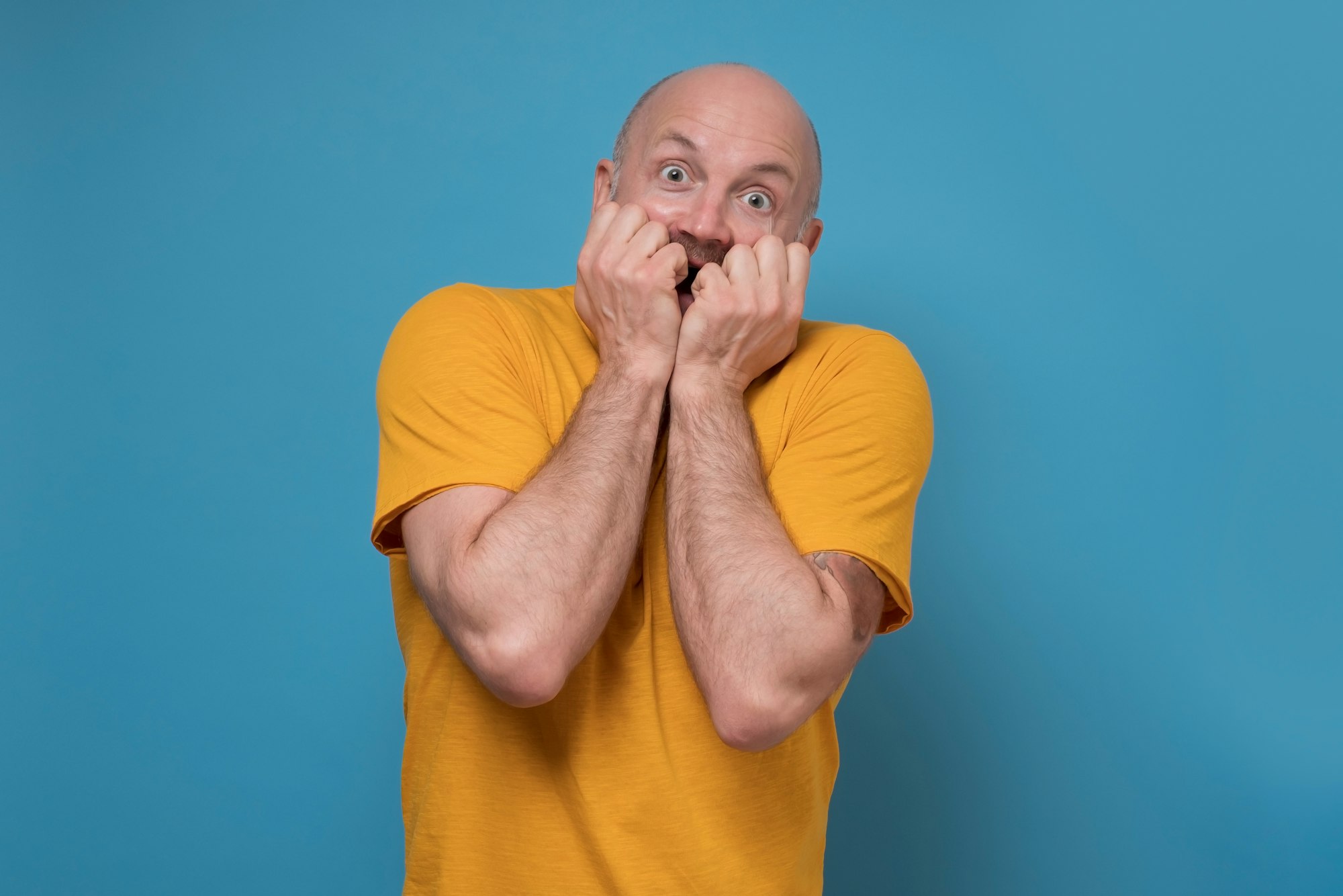 Mature man covering mouth with hands experiencing deep astonishment