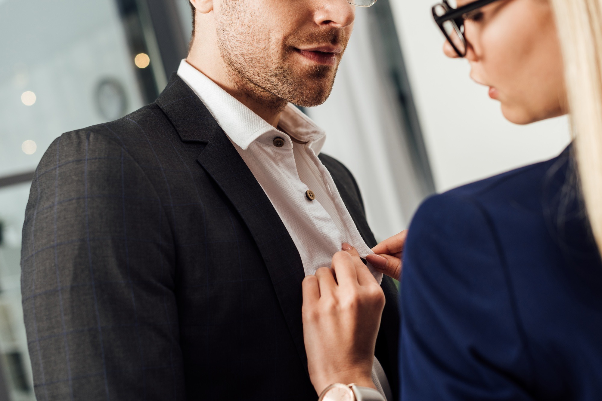 partial view of businesswoman undressing colleague in office, flirting and office romance concept
