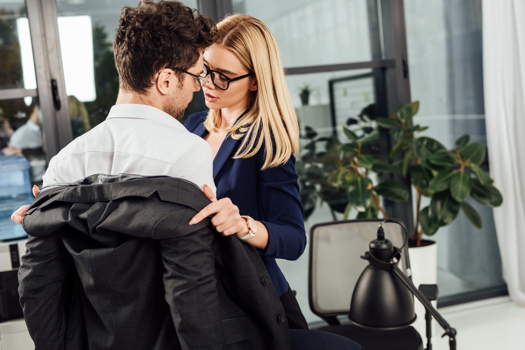 young businesswoman undressing colleague in office, flirting and office romance concept